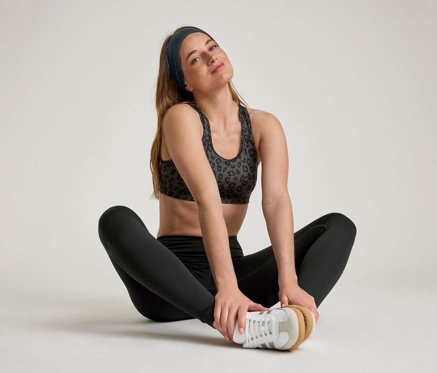 Nő ül terpeszben, fekete sportnadrágot visel.