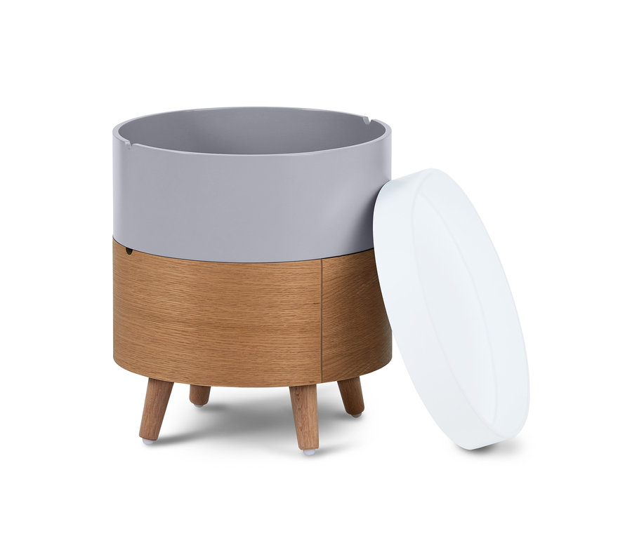 Egy kerek dohányzóasztal, emeletes, szürke felső résszel és fa alsó résszel, fehér alapon áll, a fehér fedél nyitva van.