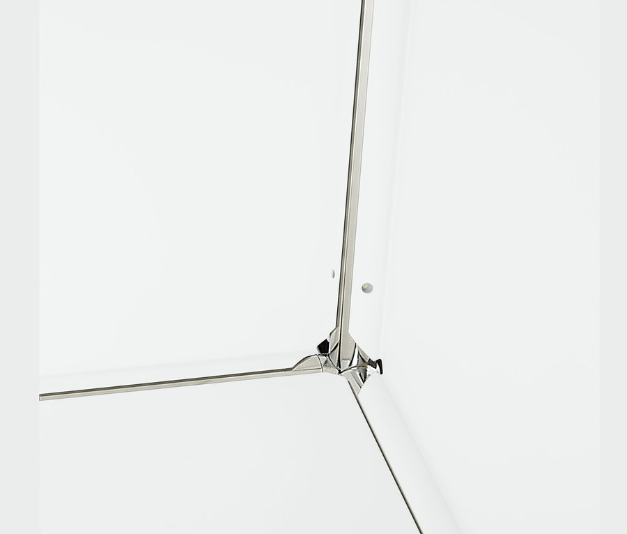 Egy fehér, fém polcos komód sarokrészlete, 2 ajtóval.