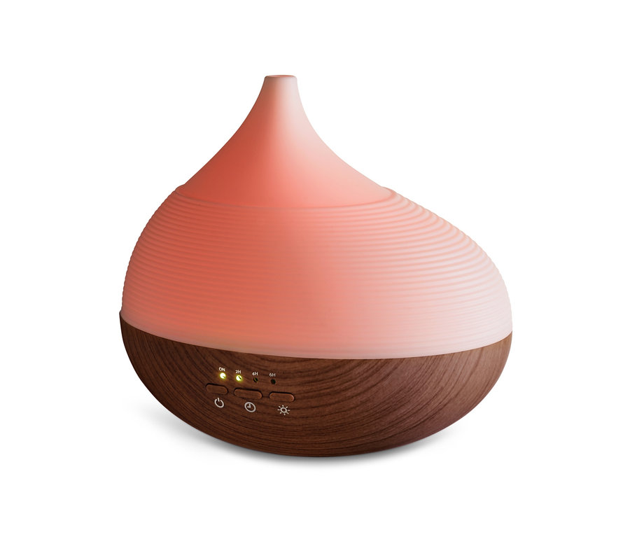 Egy aroma diffúzor közeli képe wellness világítással, a teteje világos rózsaszín, az alja pedig fa textúrájú.