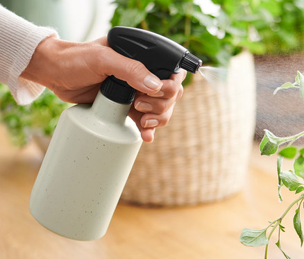 Nő permetezi a növényt egy növény permetezővel.