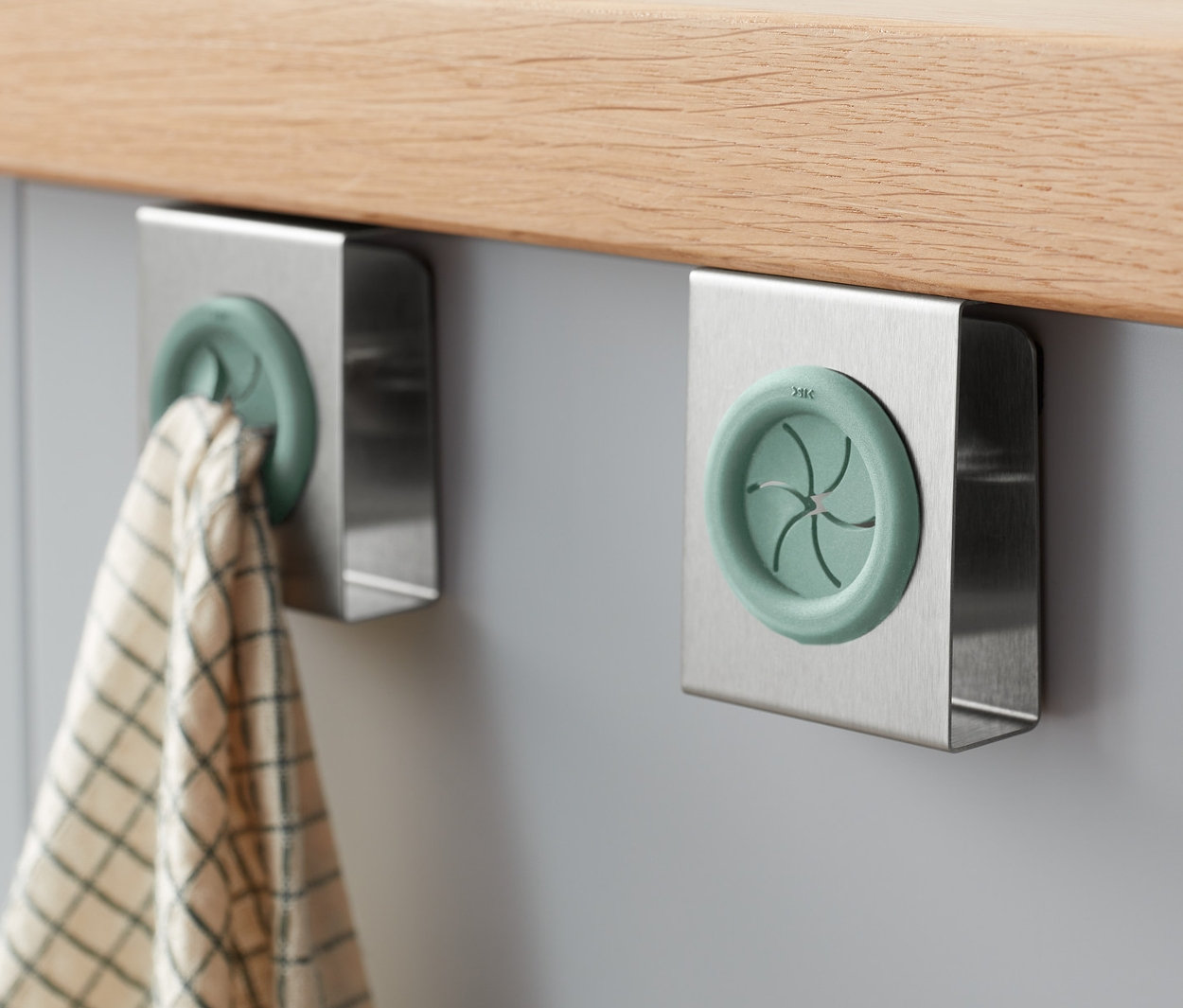 Két beakasztható konyharuha tartó van a szekrényre rögzítve, az egyiken konyharuha lóg.