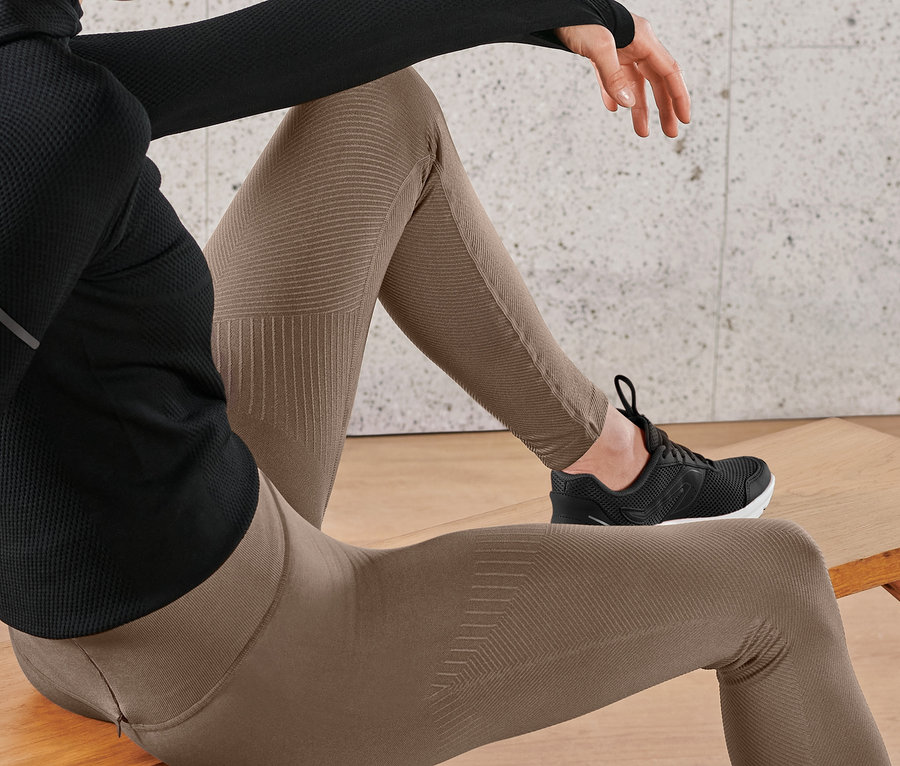 Nő ül a padon, barna női seamless futónadrágot és fekete tornacipőt visel.