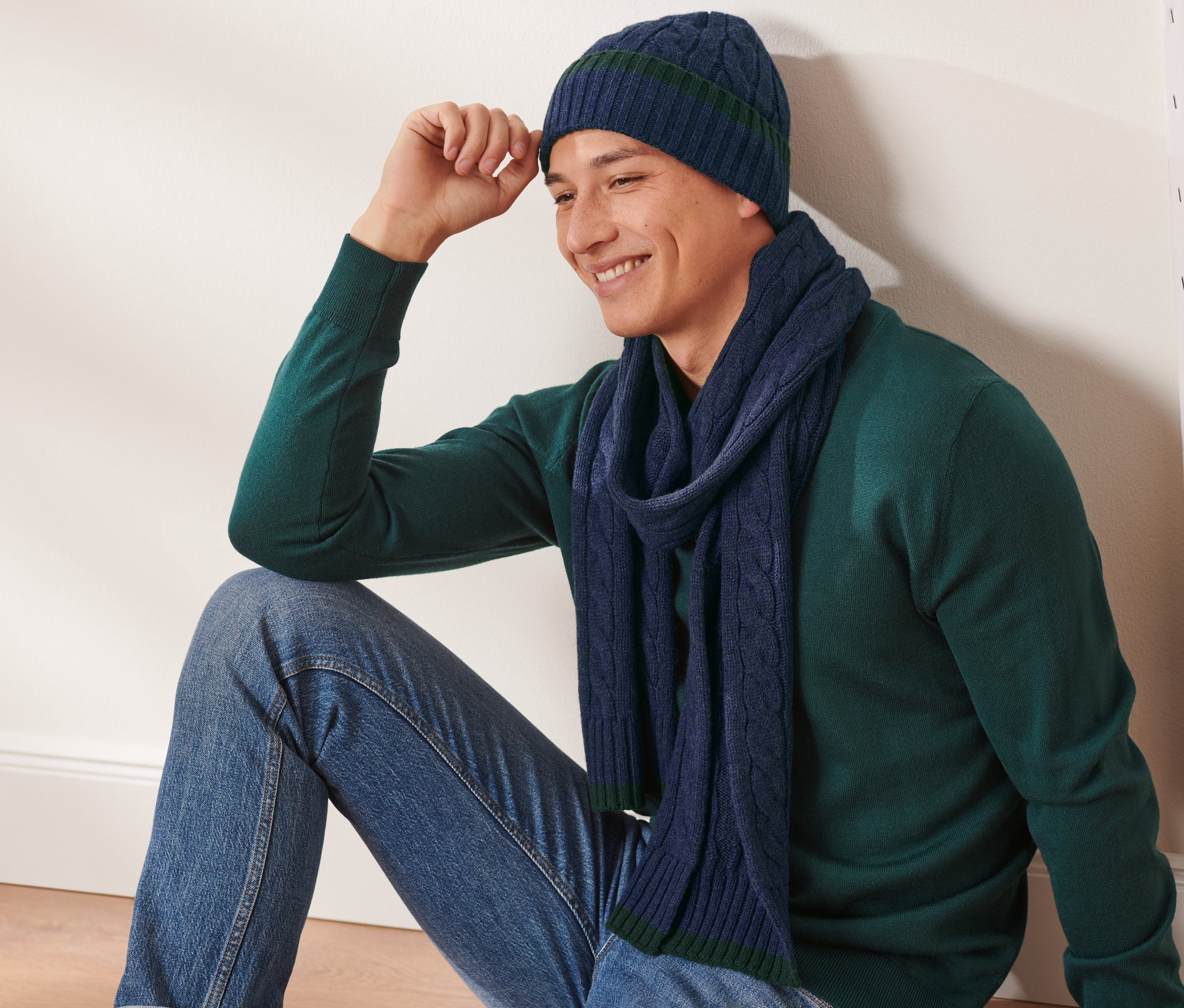Egy férfi ül, és Férfi kötött sapka és sál van rajta, gyapjúval, sötétkék.