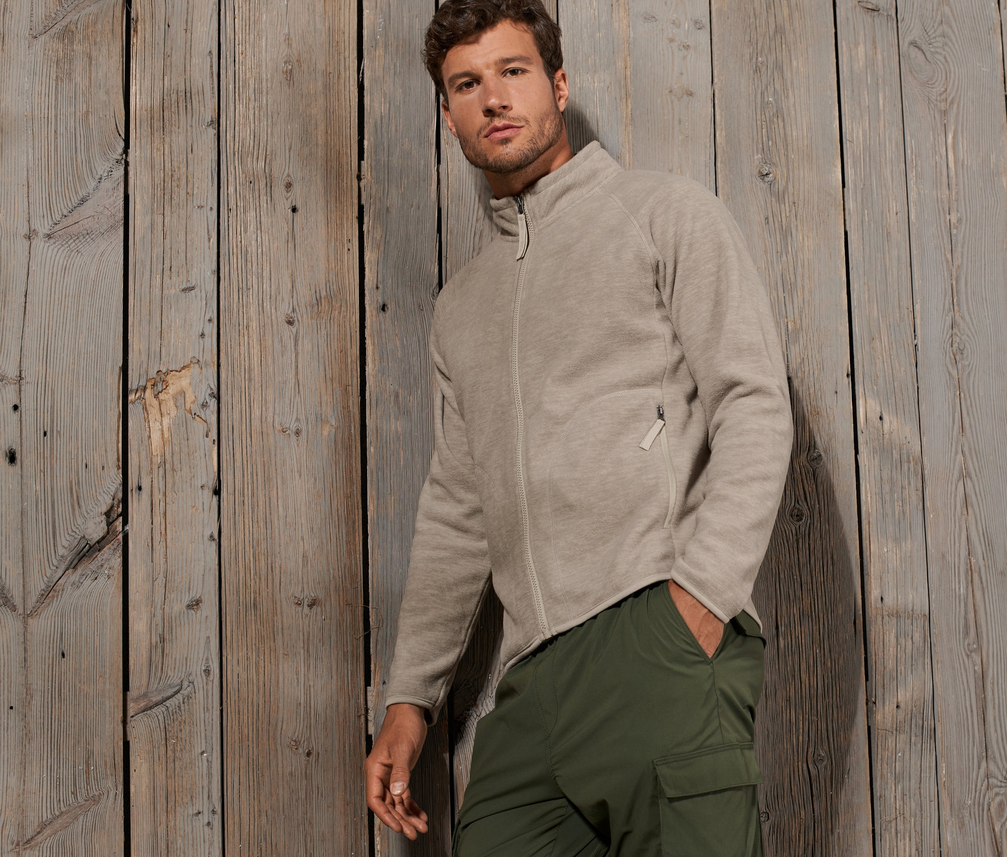 Férfi pózol bézs színű polárfelsőben.