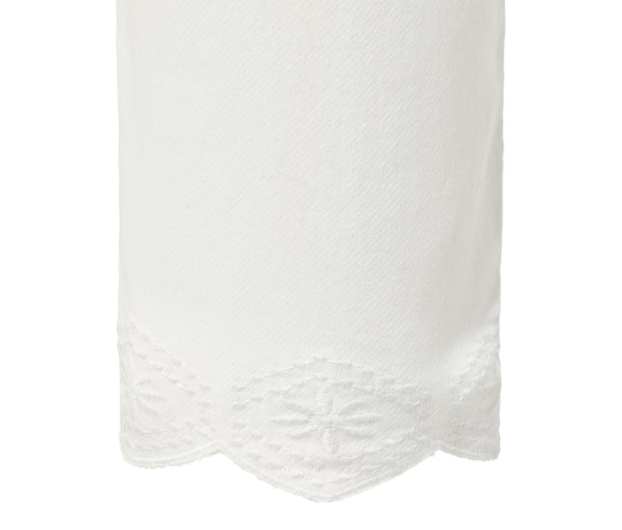 Egy fehér, 7/8-os treggings részlete lyukhímzéssel a szegélyén.