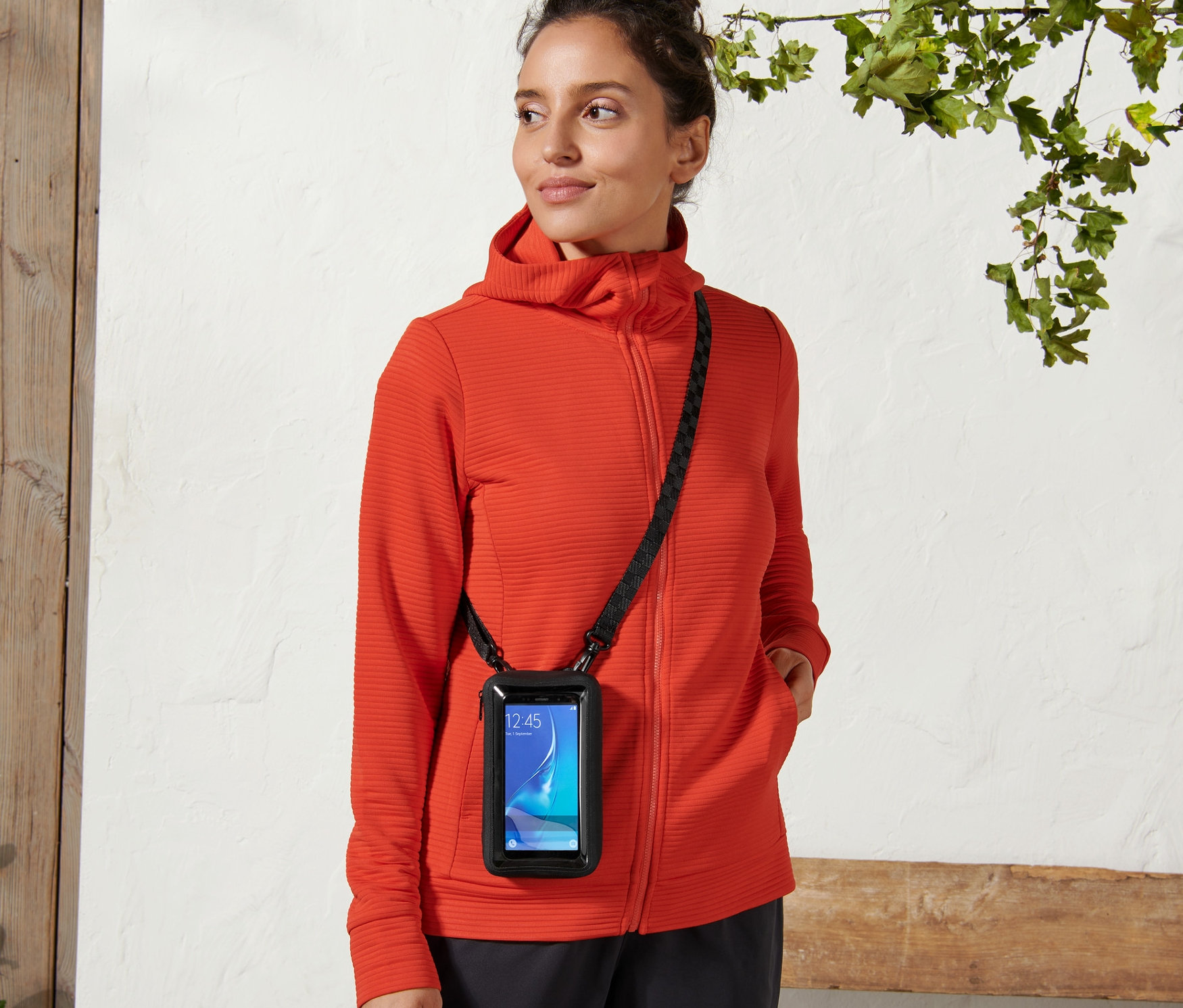 Nő visel egy 2 az 1-ben okostelefon-táskát fekete pánttal a testén.