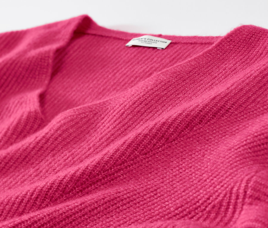 Egy málna színű, laza kötésű pulóver részlete.