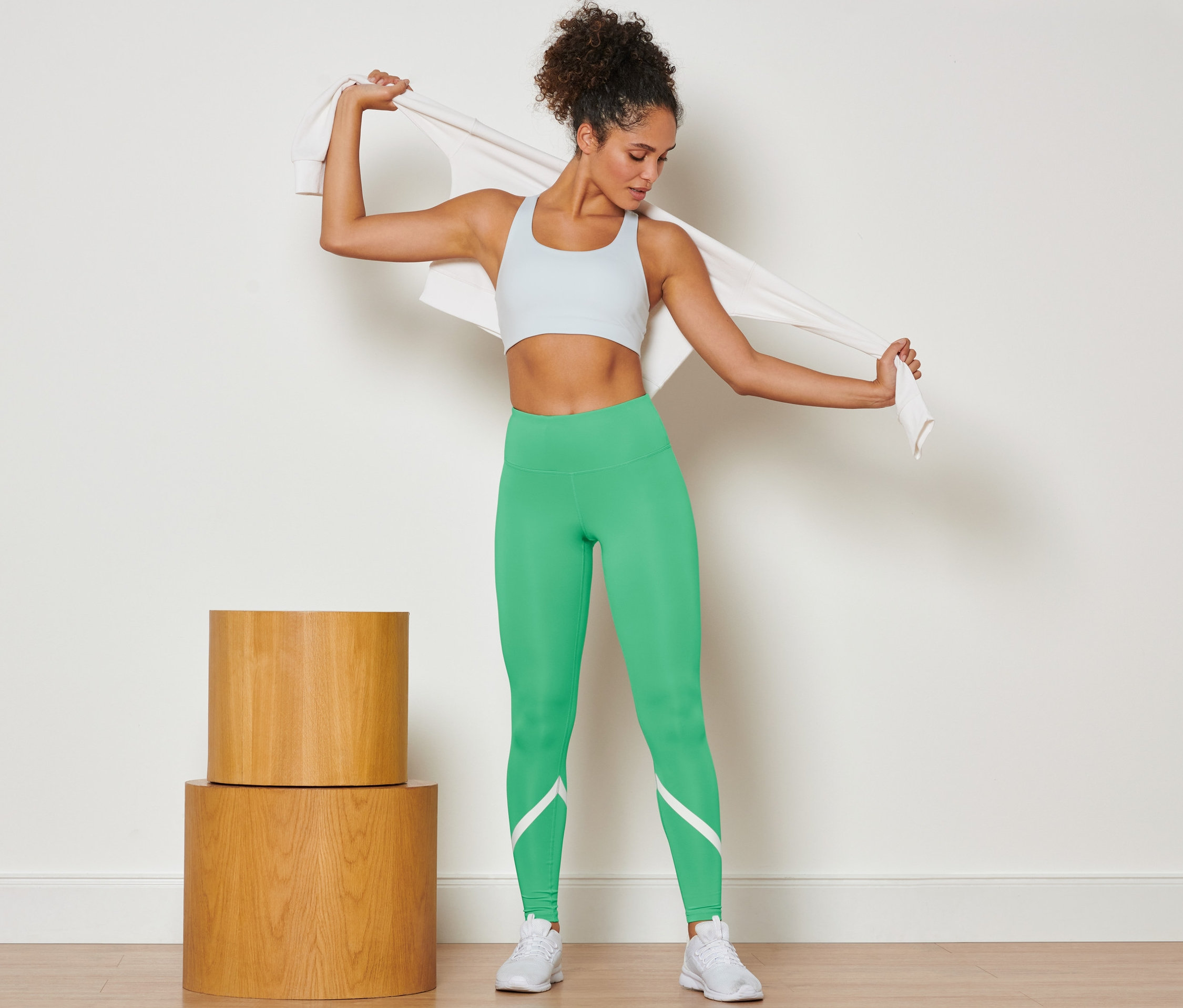 Nő törölközőt terít a vállára és zöld sportnadrágot visel.