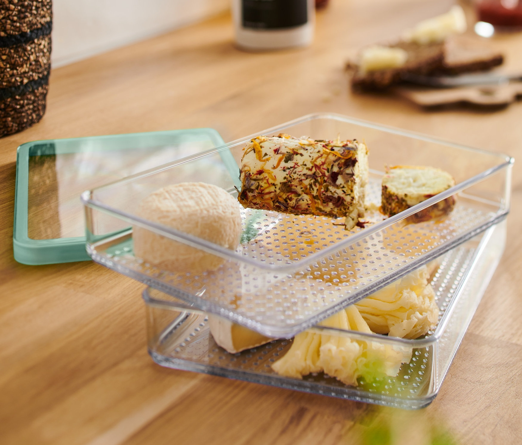 Két egymásra rakott, átlátszó Felvágottároló edény különféle sajtokkal megtöltve.