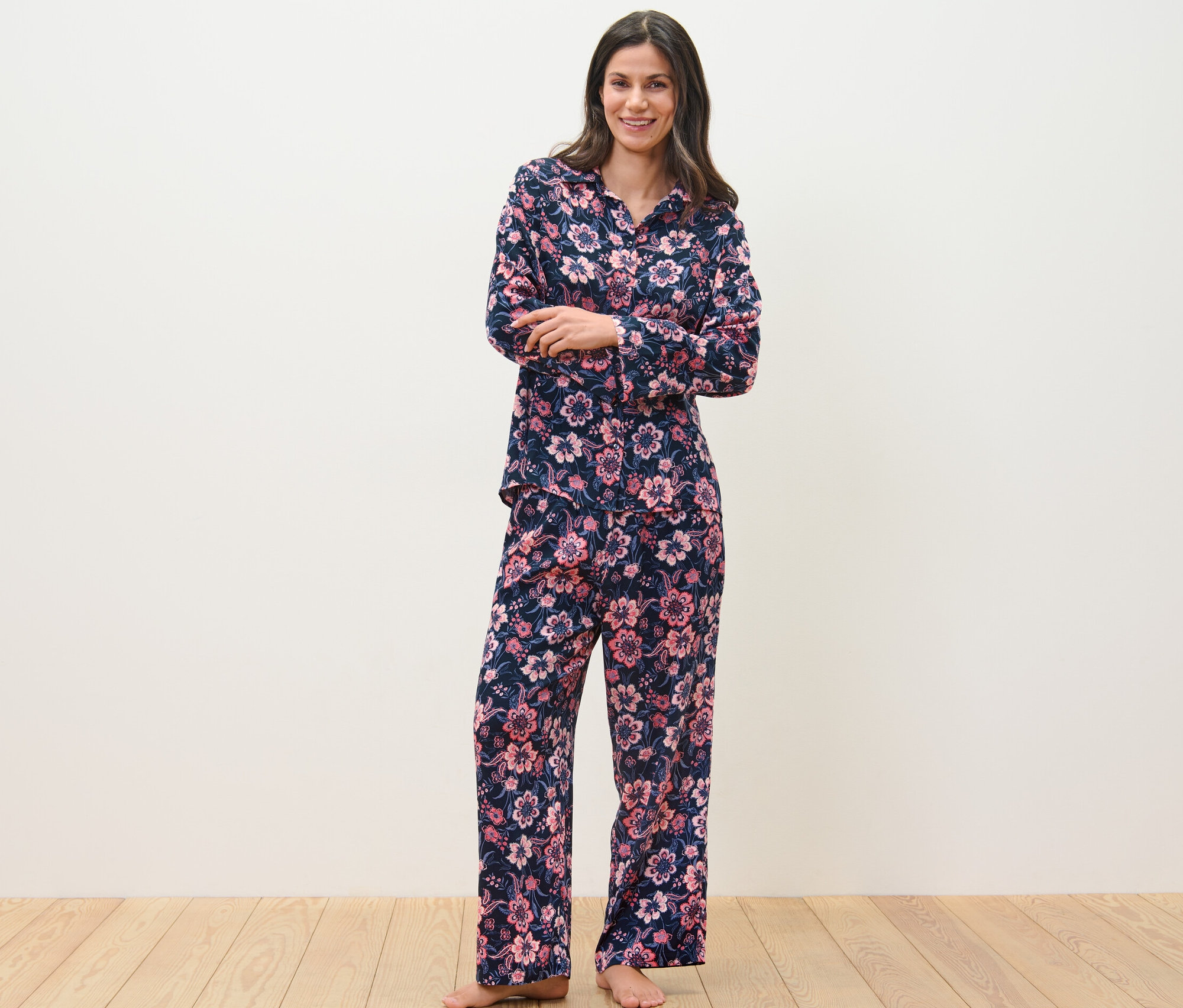 Egy nő áll virágmintás, gombos női szövött pizsamában.