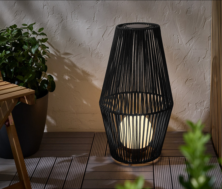 Nagy, textilpántos napelemes viharlámpa áll egy teraszon.