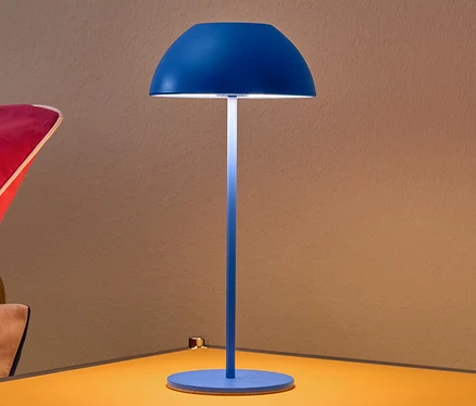 Kék LED-es asztali lámpa egy sárga éjjeliszekrényen.