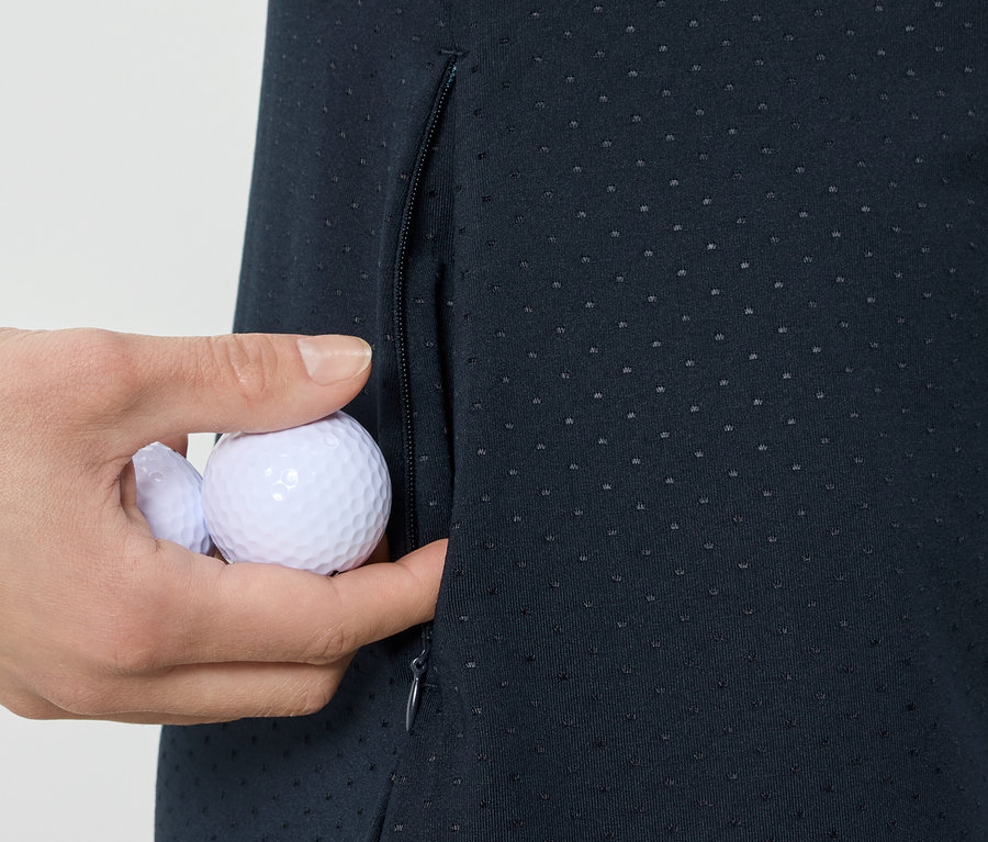 Egy kéz golf labdákat tesz egy sportruha zsebébe.