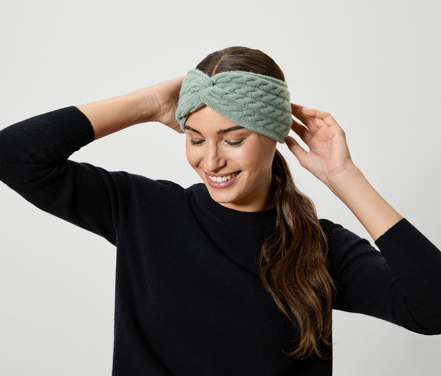 Nő igazgatja a világoszöld kötött fejpántot.