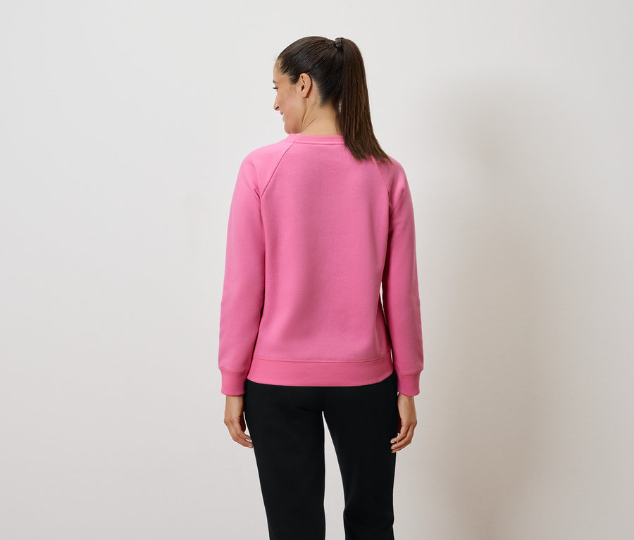 Hátulról látható nő rózsaszín pulóverben és fekete nadrágban.