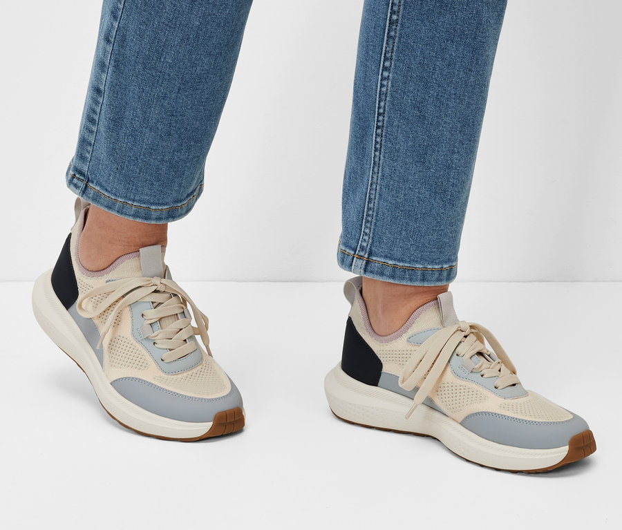 Farmernadrágot és sneakercipőt viselő lábak fehér háttér előtt.