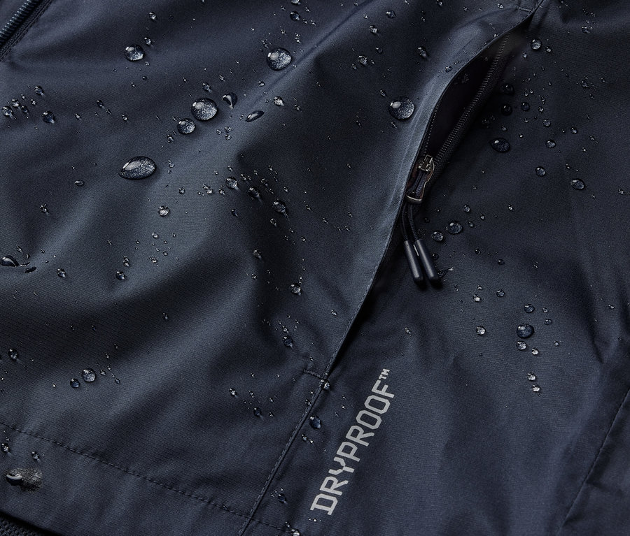Egy tengerészkék esőkabát részlete cipzáras zsebbel és DRYPROOF felirattal.
