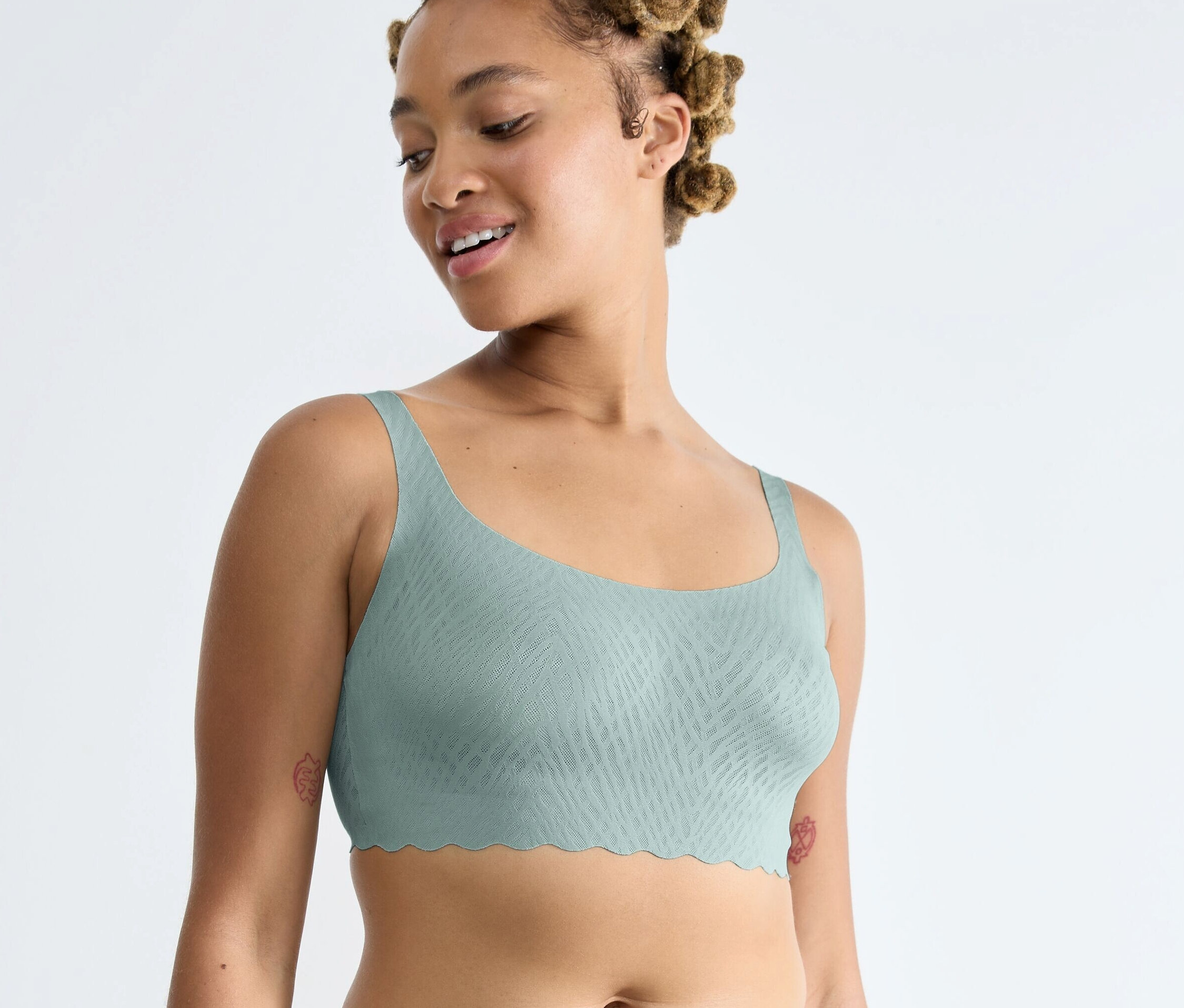 Nő visel egy ködös türkiz színű Sloggi ZERO Feel Bliss topot.