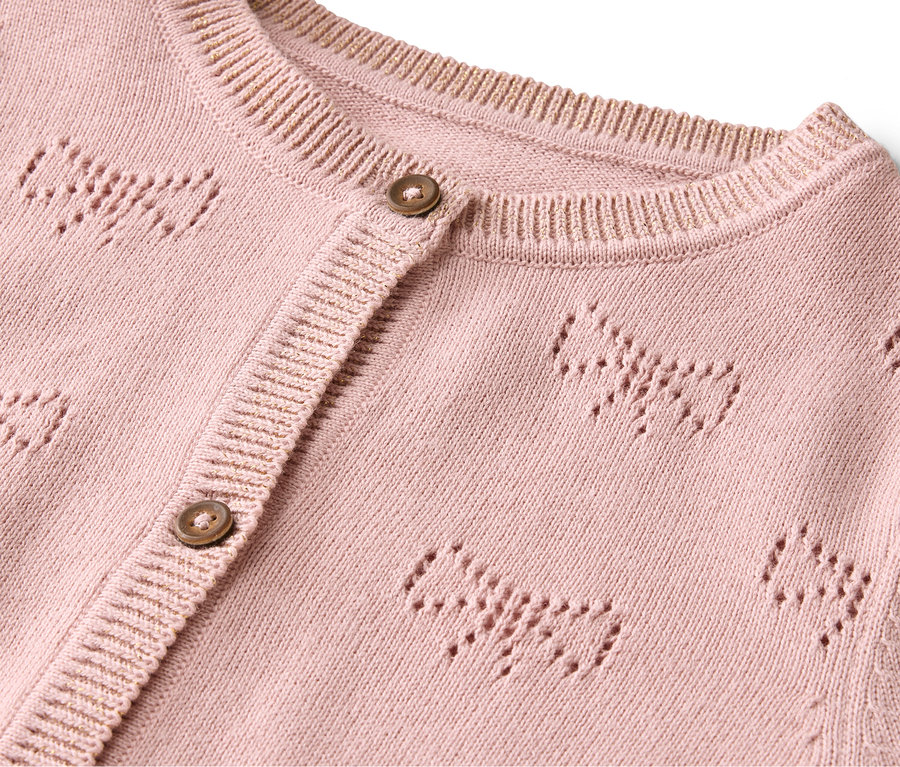 Egy rózsaszín kardigán részlete gombokkal és masni mintával.