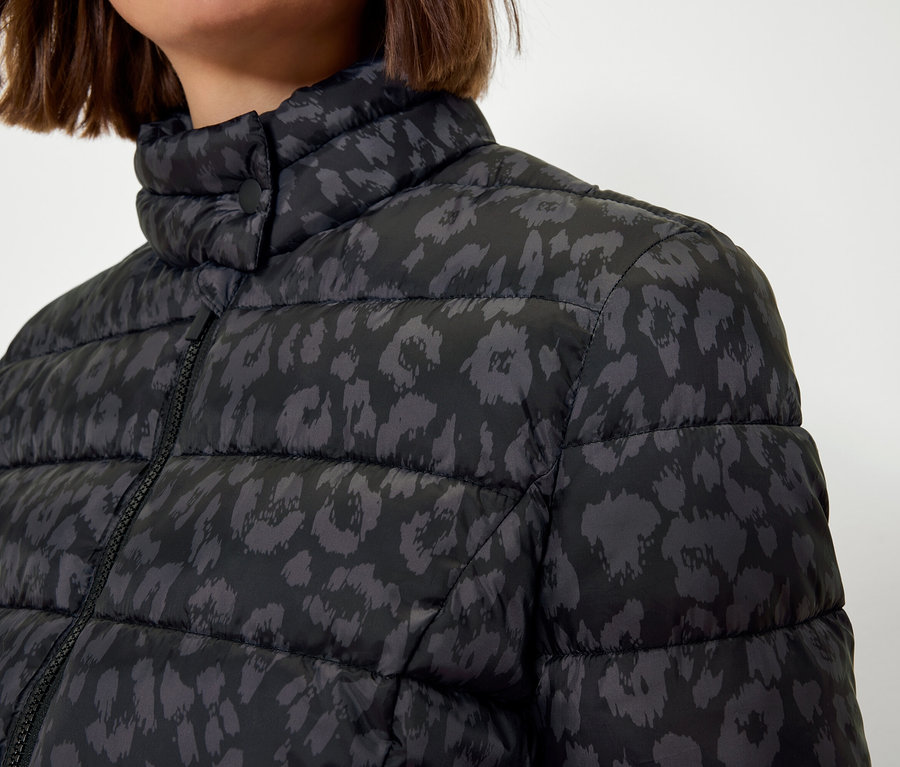 Egy nő felsőteste fekete, steppelt, állatmintás kabátban.