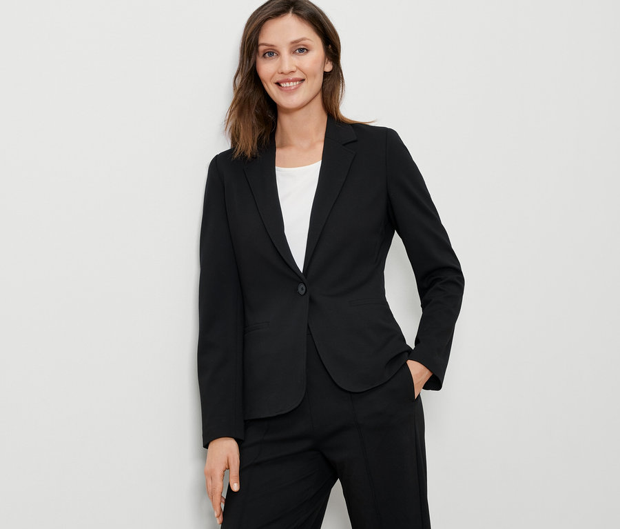 Nő visel egy fekete jersey blézert.