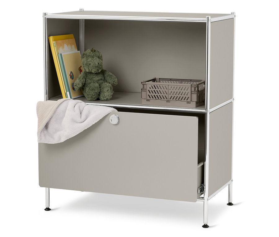 Szürke polc egy plüssmackóval, könyvekkel, egy szürke dobozzal és egy fehér törölközővel.