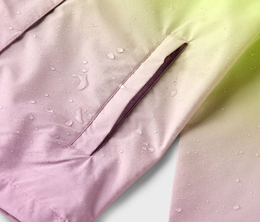 Egy rózsaszínből sárgába hajló, vízálló kabát közeli felvétele, esőcseppekkel és oldalzsebbel.