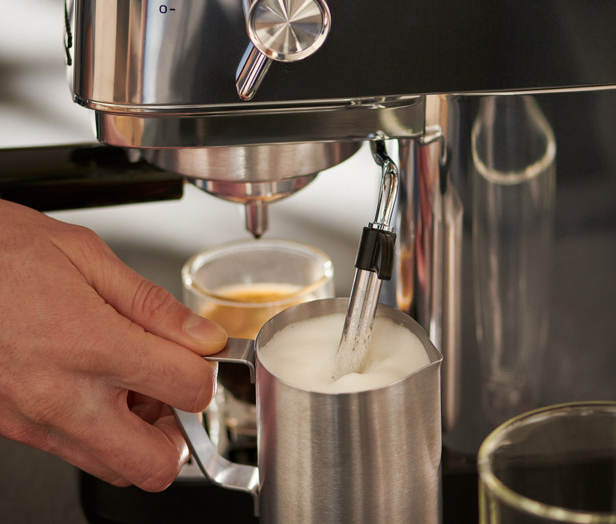 Férfi használ egy ezüst »Lapressa« karos eszpresszó kávéfőzőt és egy 300 ml-es rozsdamentes acél tejeskancsót.