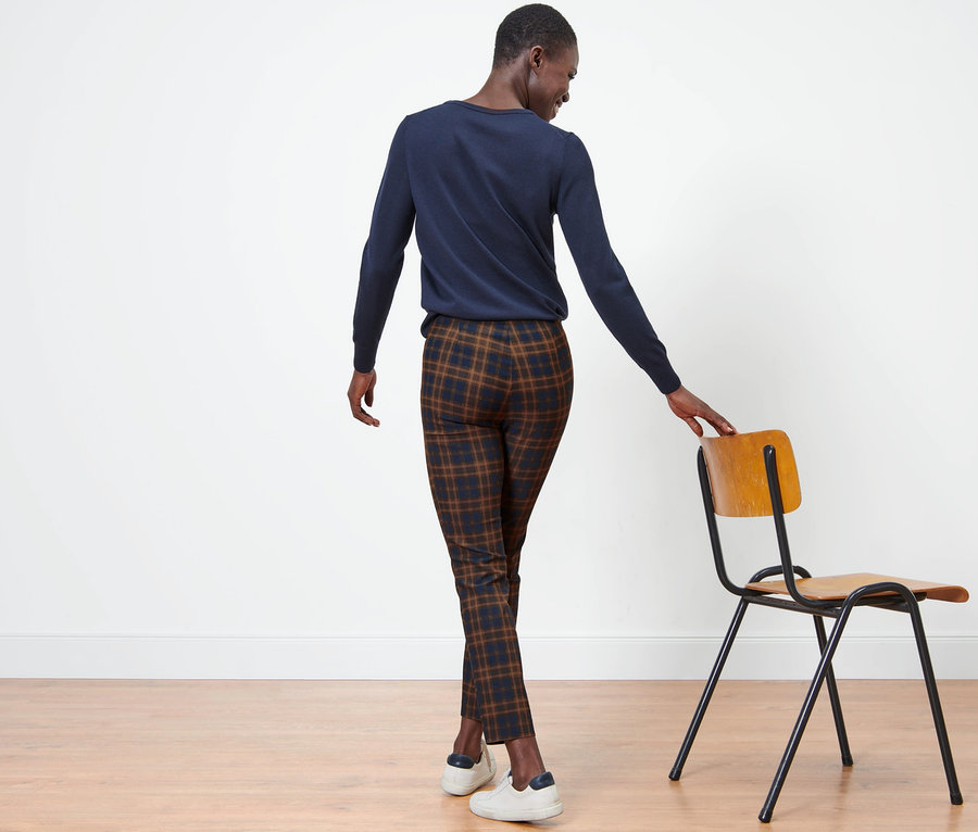 Egy nő háttal áll a kamerának, kockás sztreccsnadrágot visel.