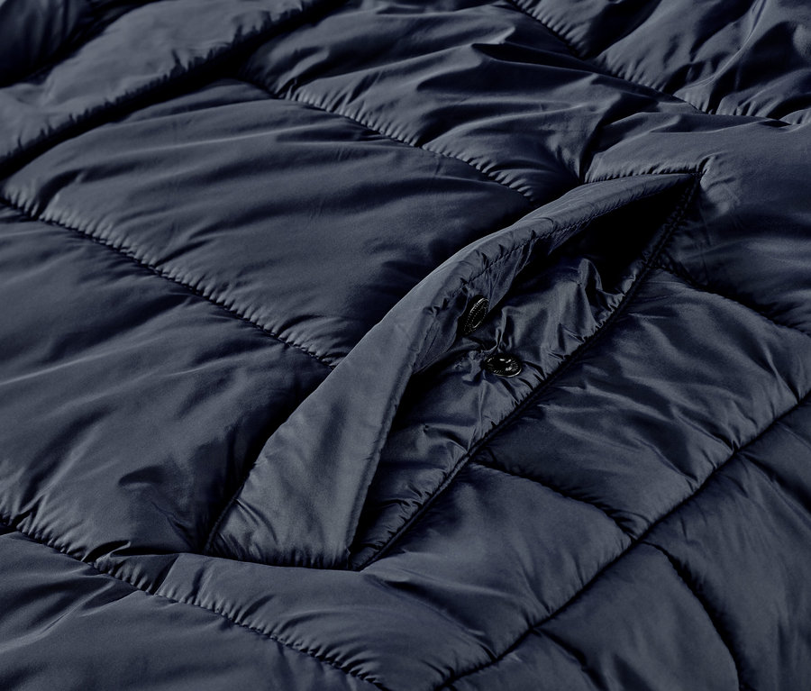 Egy női hosszú, sötétkék steppelt mellény részlete.