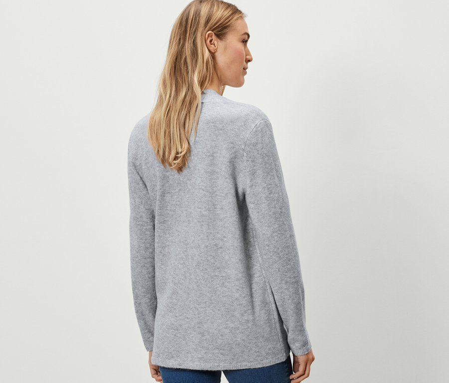 Nő visel egy szürke, nyitott kötött kardigánt.