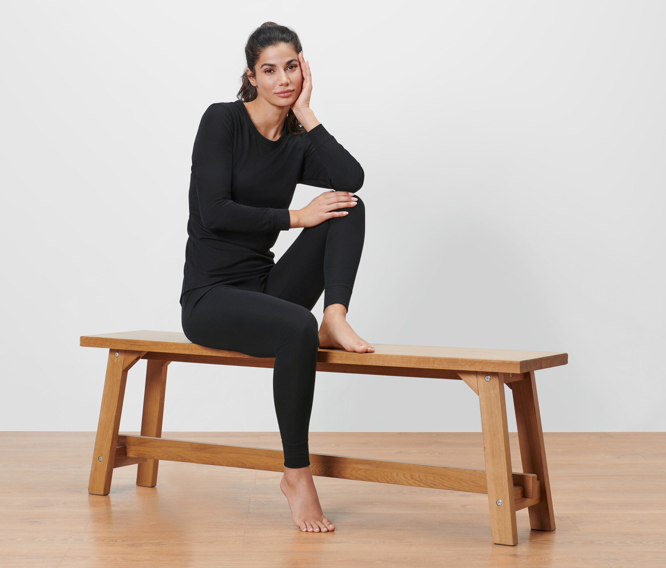 Nő ül egy padon fekete funkcionális termo aláöltözetben.