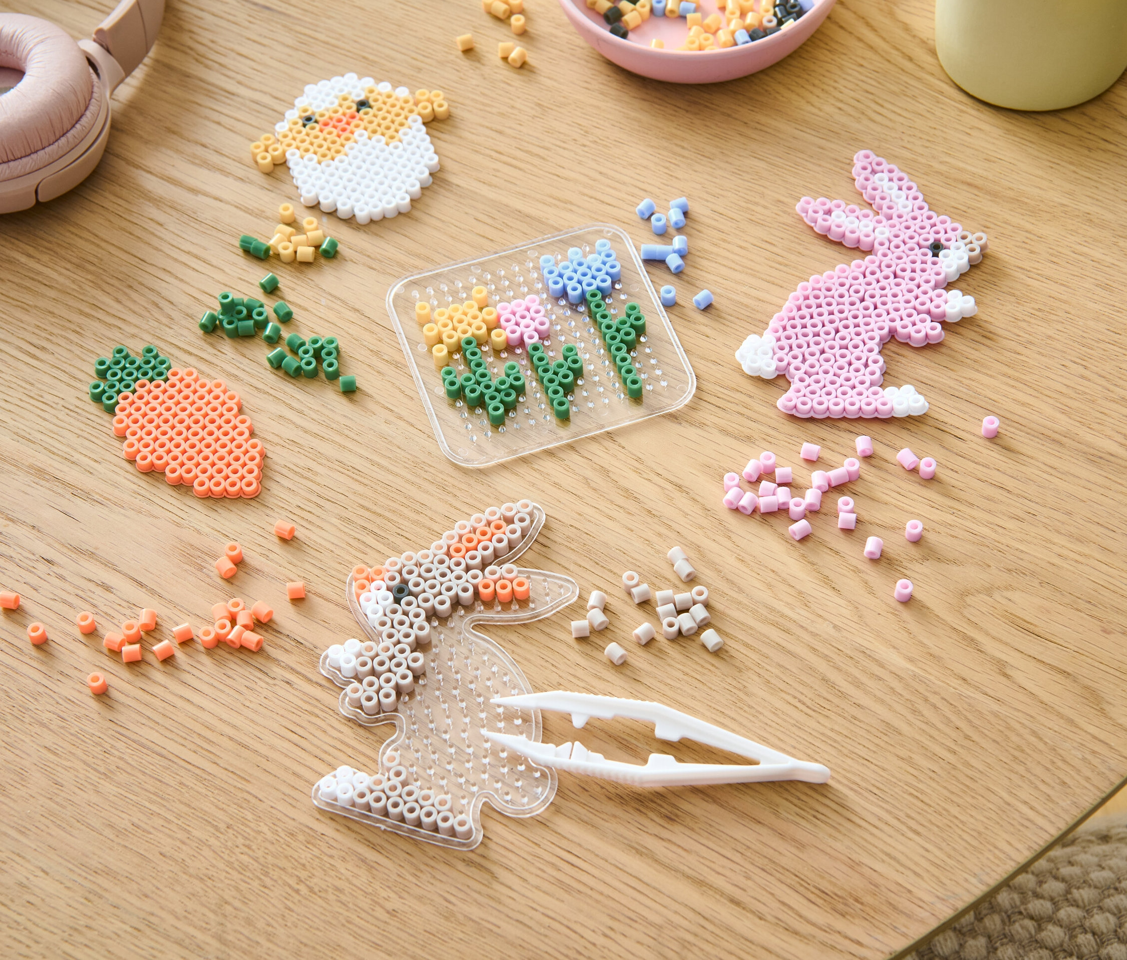 Az asztalon egy vasalható gyöngy készlet és különböző színű gyöngyök találhatók.