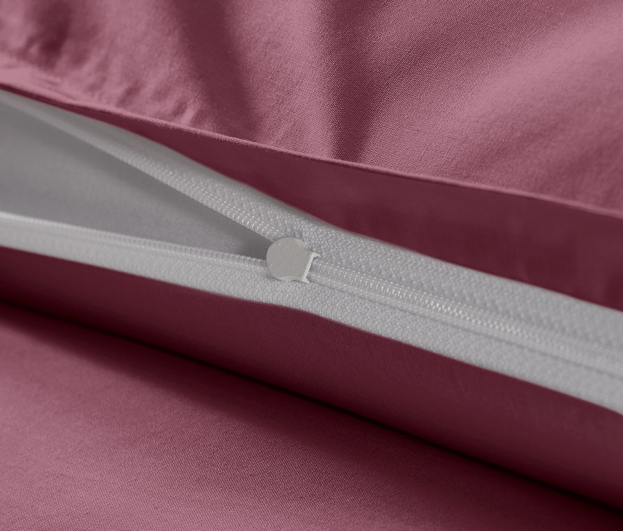 Közeli kép egy málnaszínű, extra méretű pamutszatén ágynemű cipzárjáról.