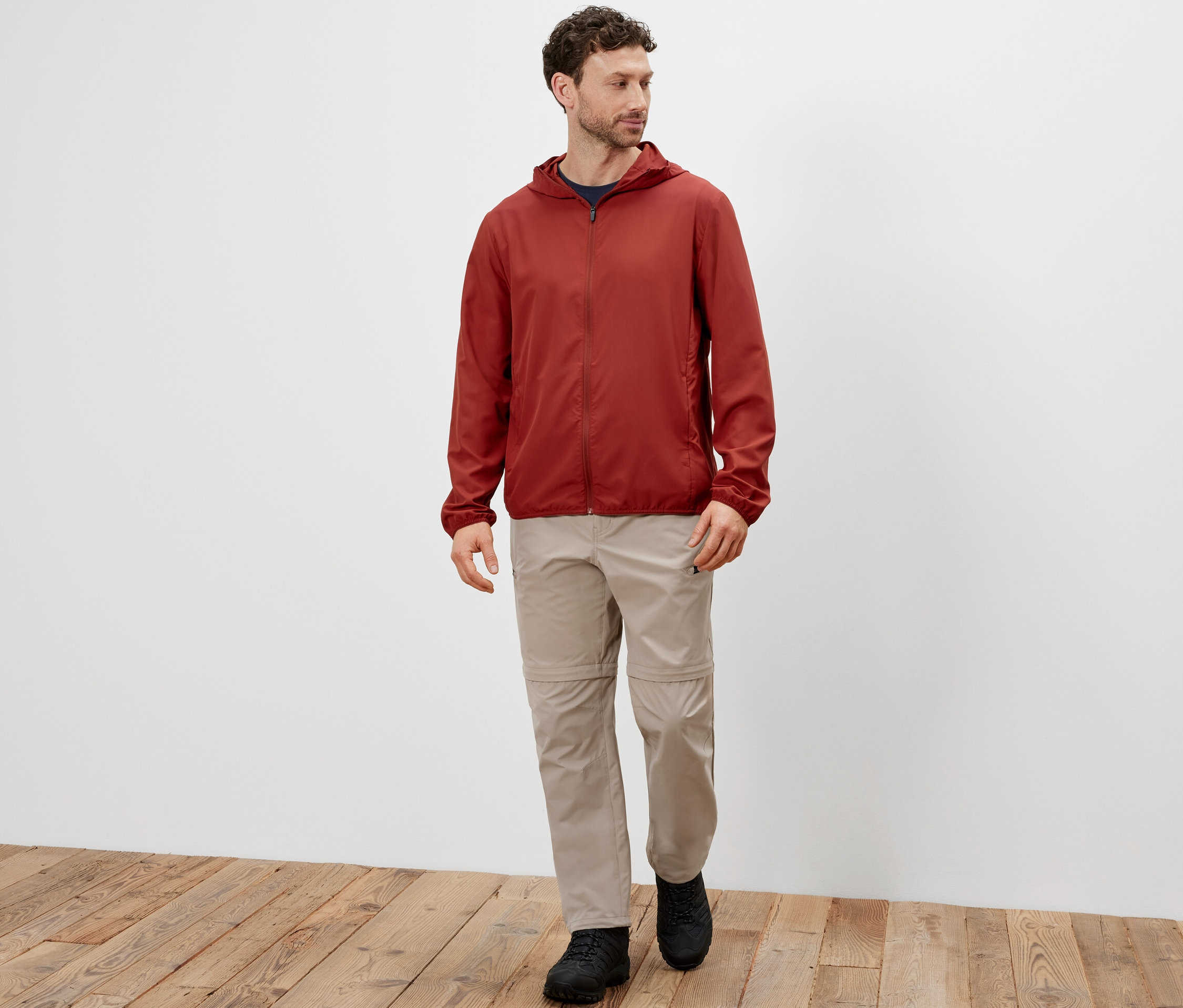 Egy férfi sétál, és egy piros, összehajtható férfi funkcionális dzsekit visel.