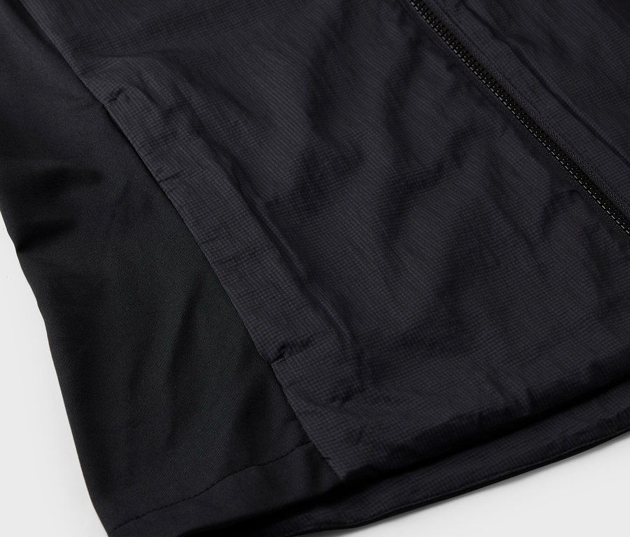 Egy fekete kabát részletes képe cipzárral és oldalzsebbel.