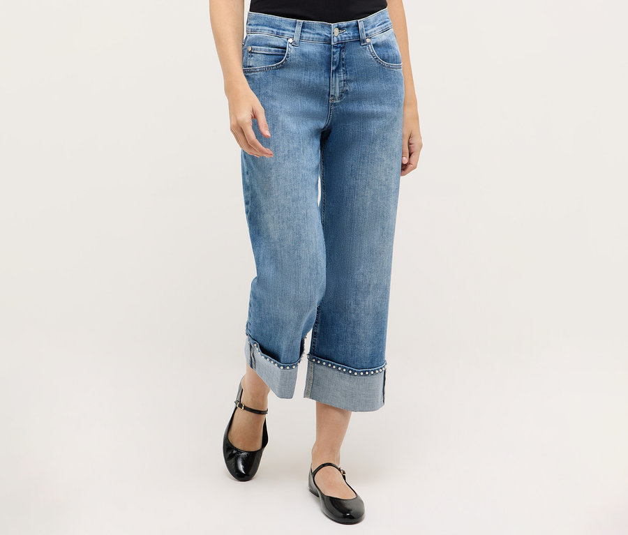 Egy nő kék Angels denim »Linn Cool« farmert és fekete Mary Jane cipőt visel.