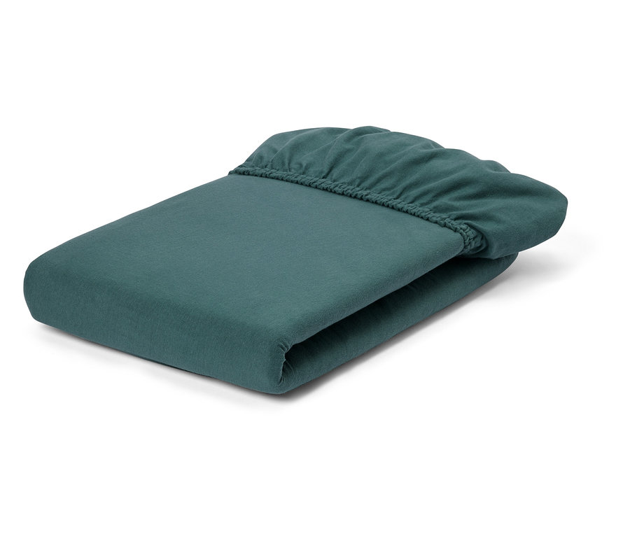 Egy összehajtott, petróleum színű gumis lepedő fekszik egy fehér háttéren.