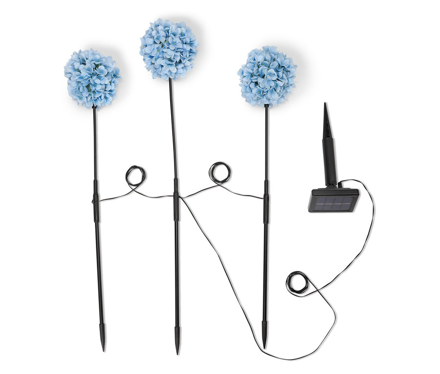Három kék hortenzia szolárlámpa fekete rúddal és napelemmel fehér háttér előtt.