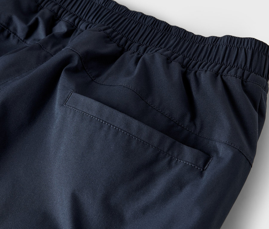 A tengerészkék színű, gumis derekú és hátsó zsebbel ellátott melegítő alsó részletes felvétele.