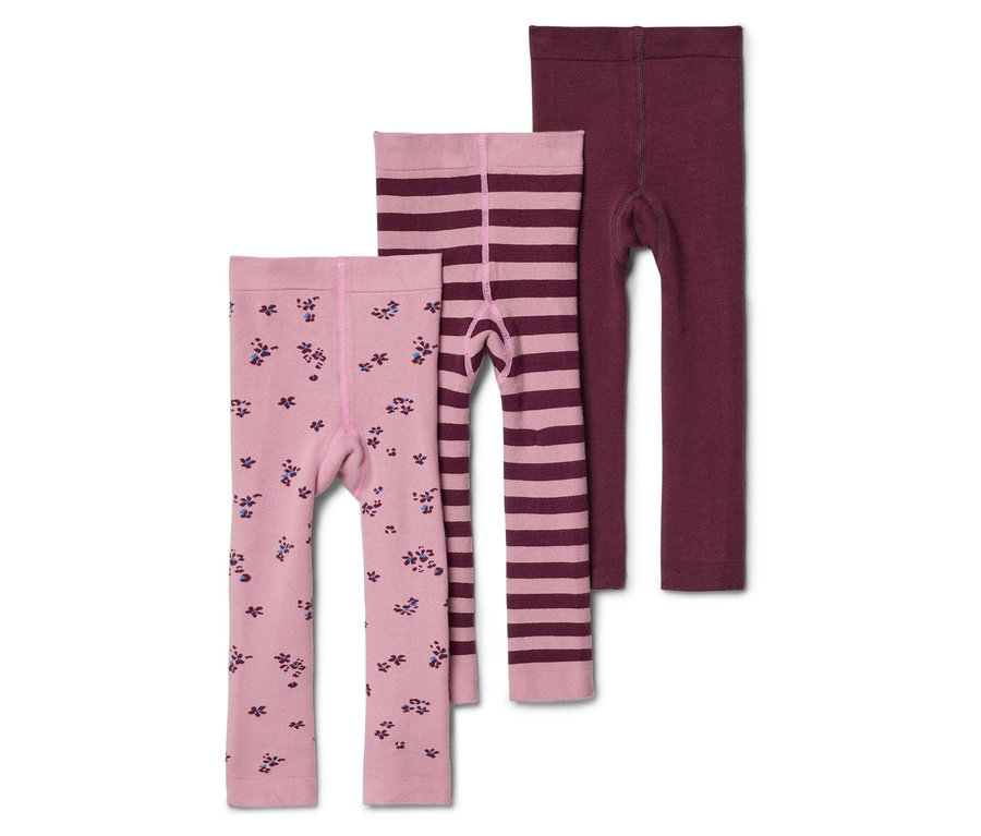 Három gyermek leggings fekszik egymáson: egy világos rózsaszín virágmintás, egy világos rózsaszín csíkos és egy bordó.