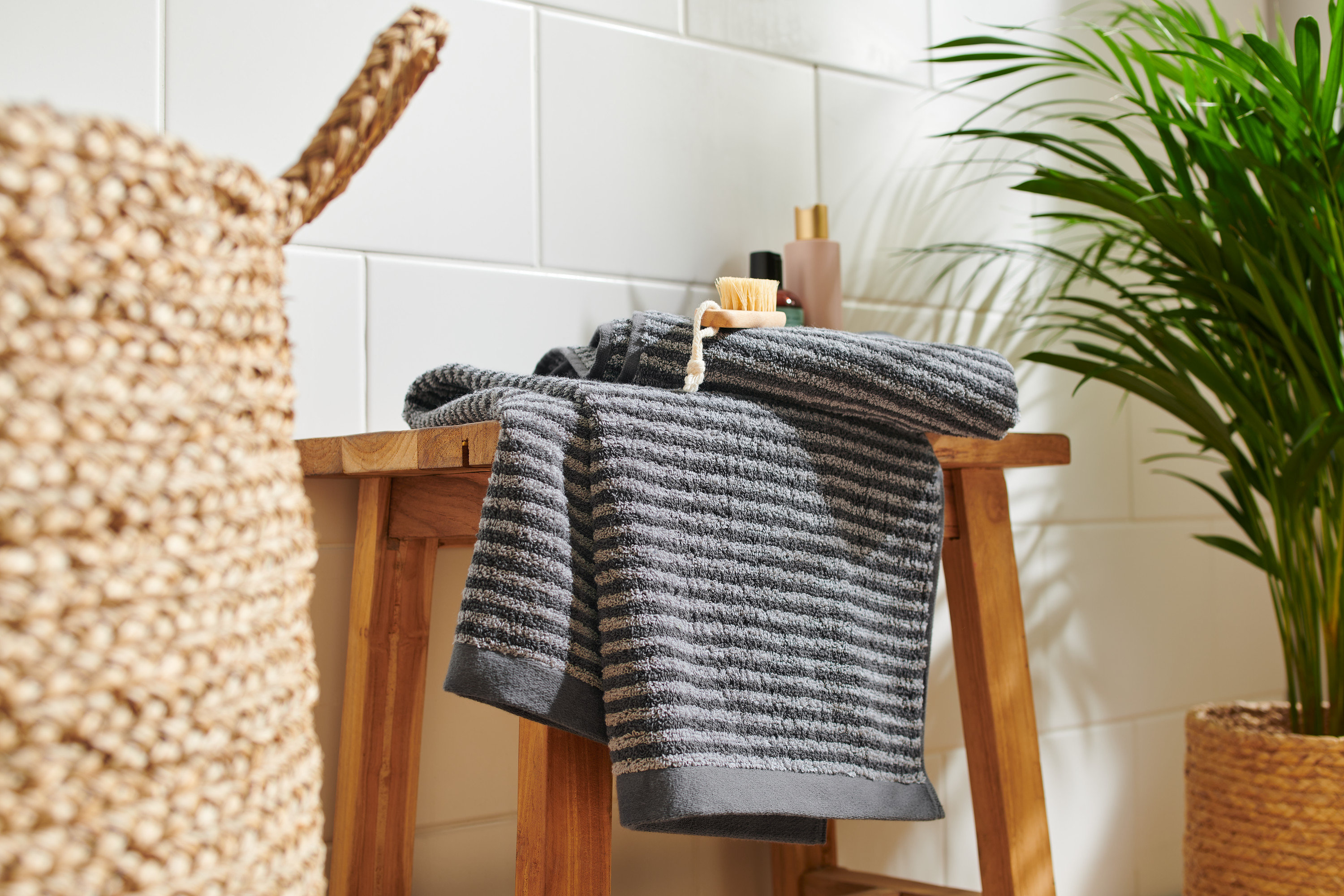 Két kiváló minőségű antracit törölköző egy fa sámlin.