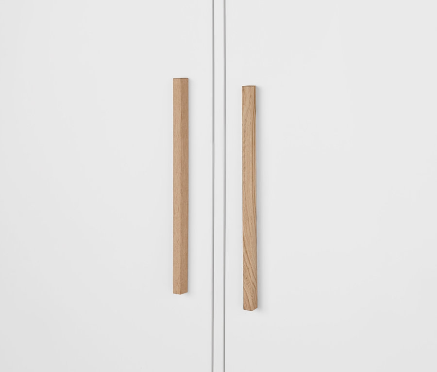 Egy fehér »Eklund« ruhásszekrény részlete fiókokkal, fa fogantyúkkal.