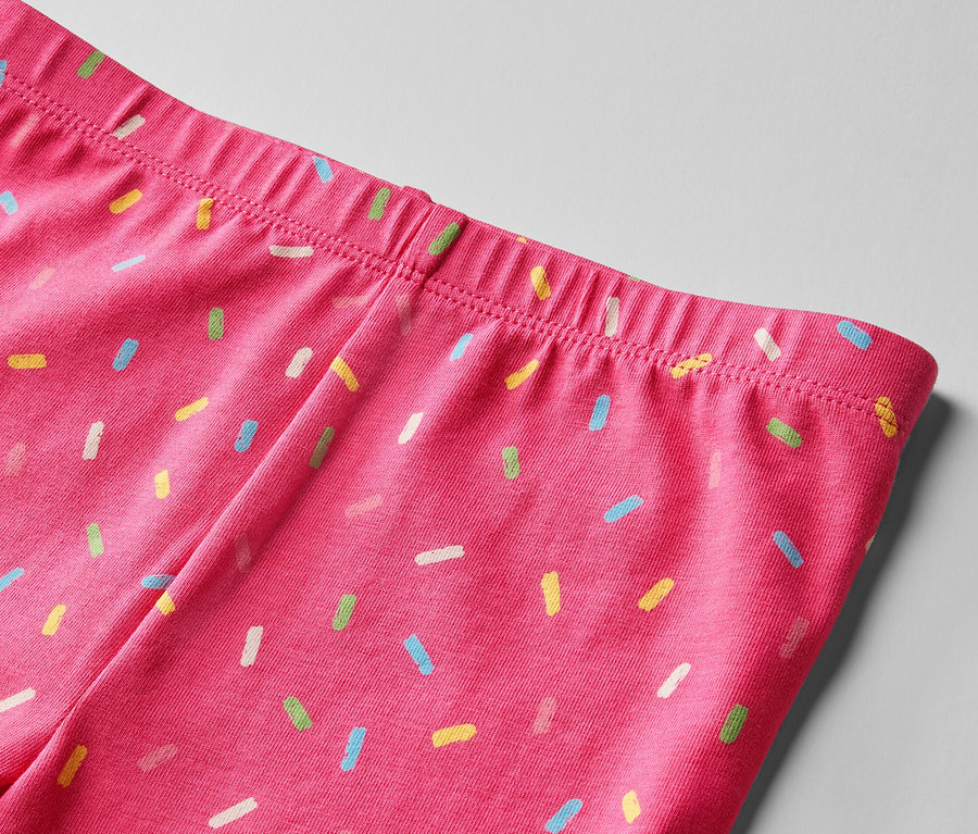 Egy rózsaszín leggings derékrészének közeli képe, színes cukorkaszórással nyomtatva. 2 kerékpáros leggings gyerekeknek, pink és sárga.