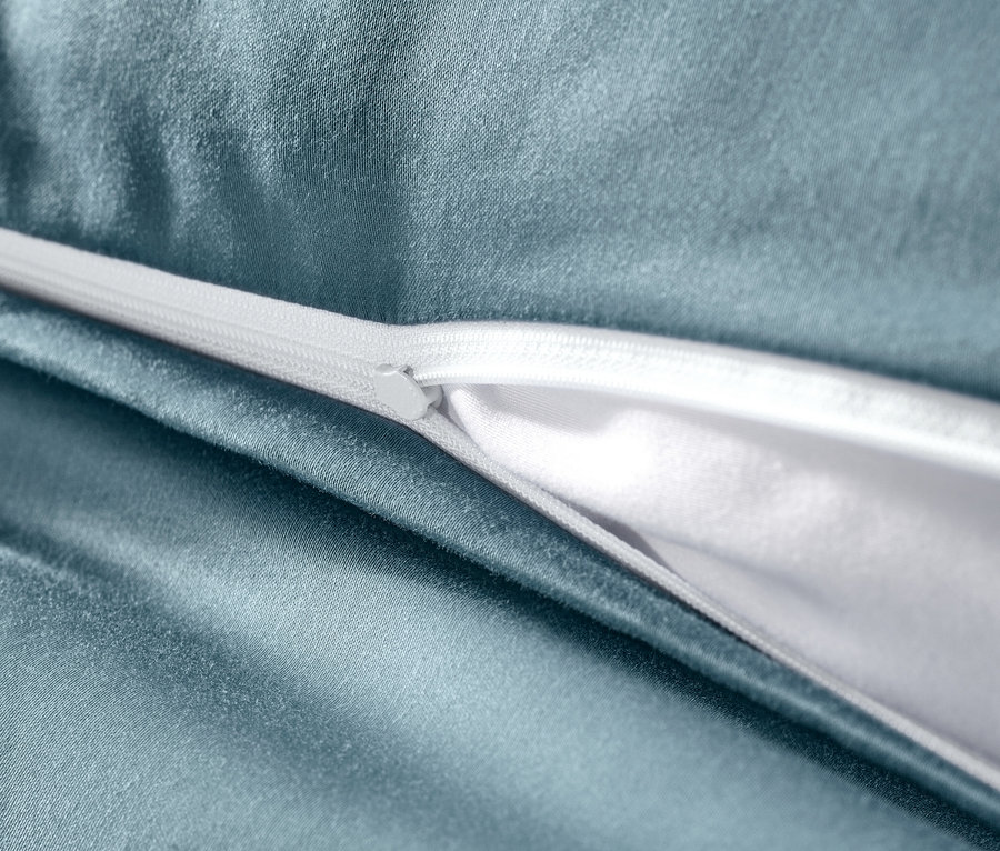 Kék pamutszatén ágynemű részlete fehér cipzárral.