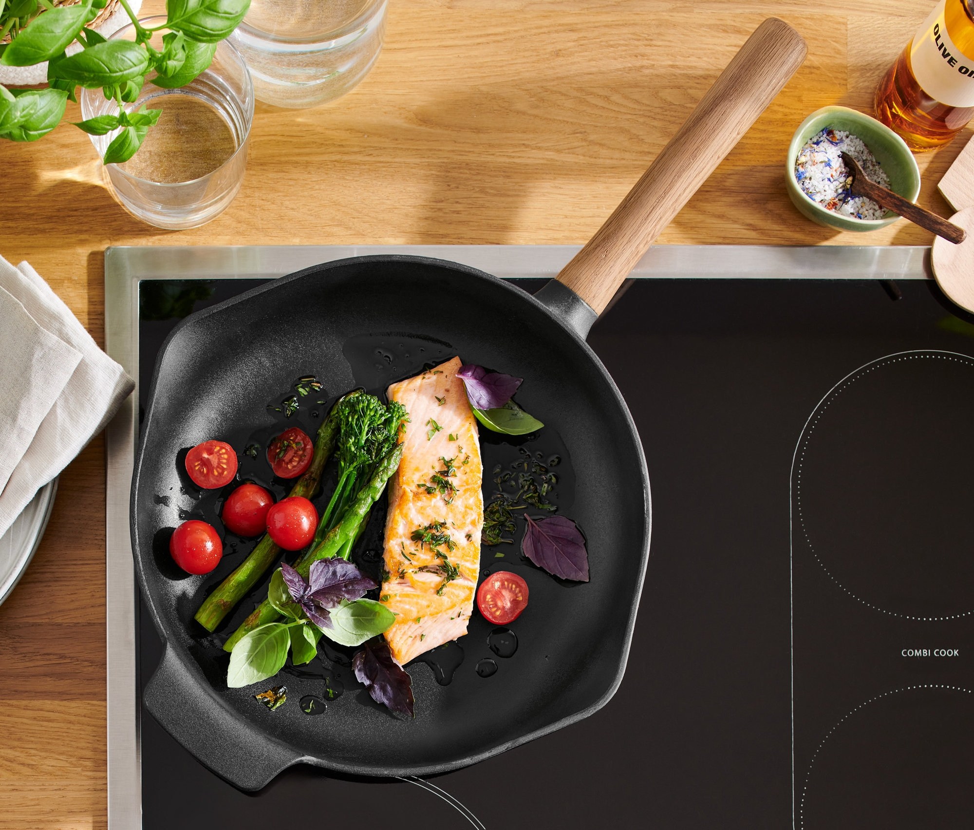 Lazac, koktélparadicsom és brokkoli egy fa nyelű öntöttvas serpenyőben.