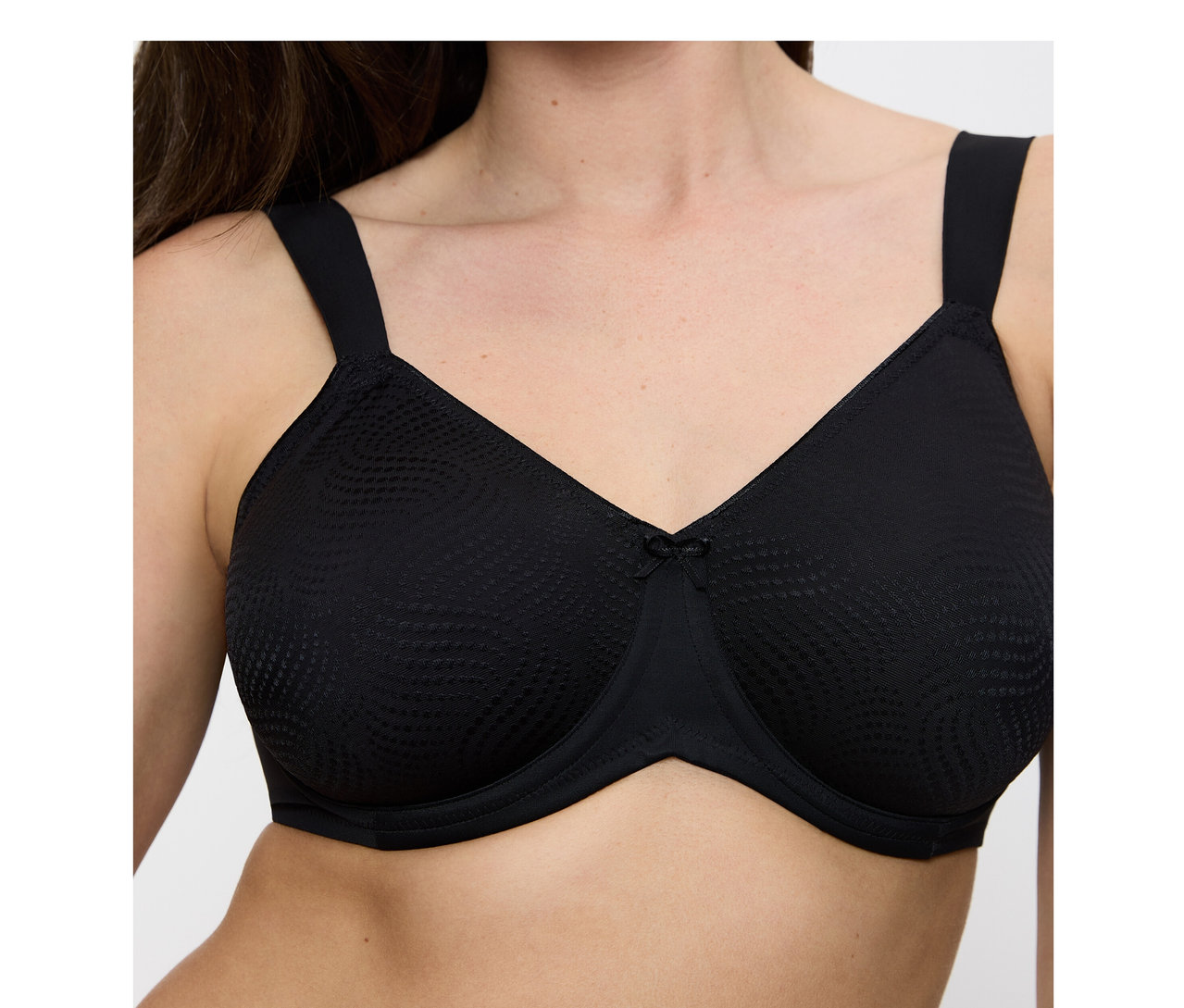 Nő visel egy fekete Triumph Essential »Minimizer W X« melltartót texturált kosarakkal és egy kis masnival.