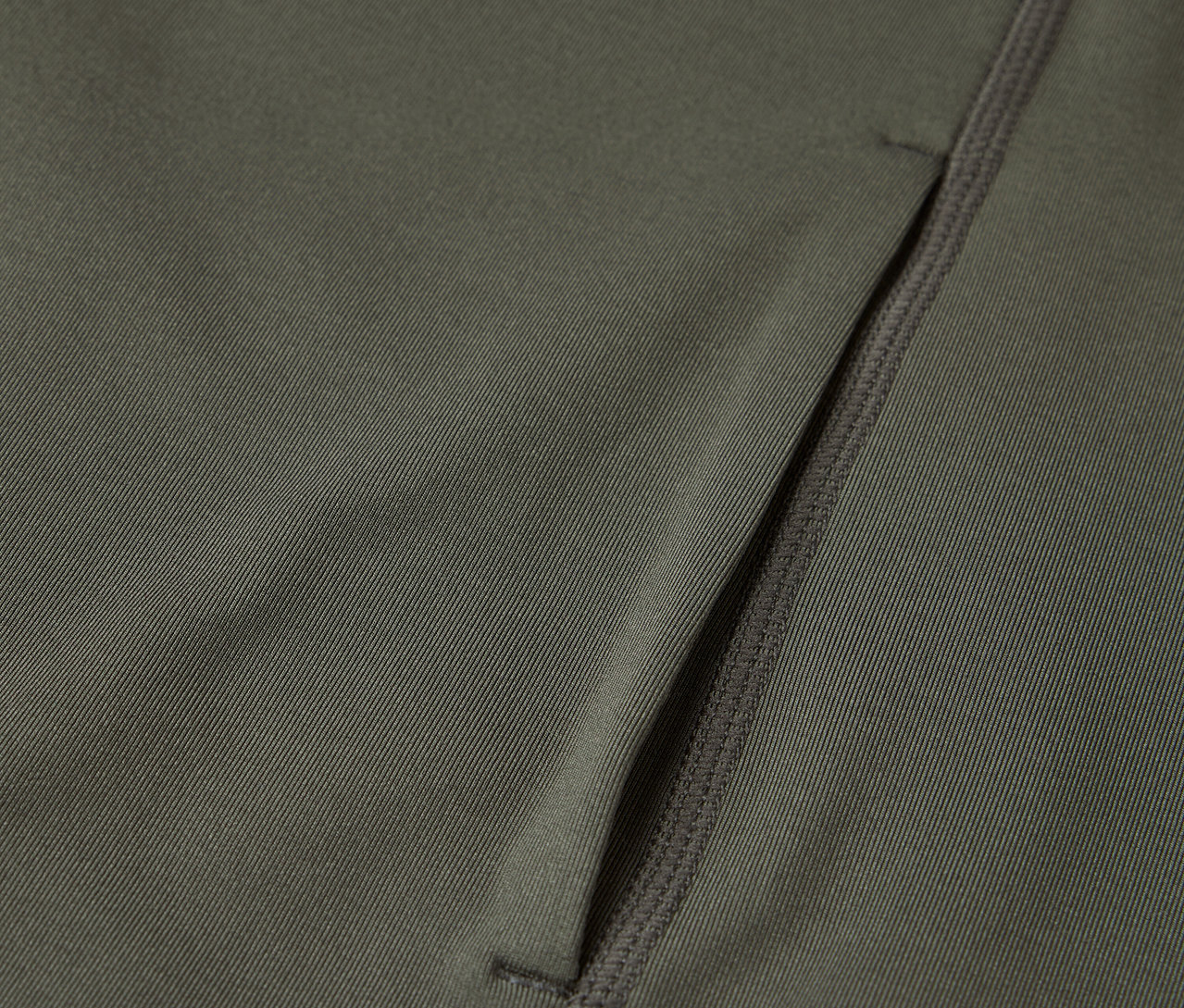Közelkép egy olívazöld szövetről, cipzáras zsebbel.