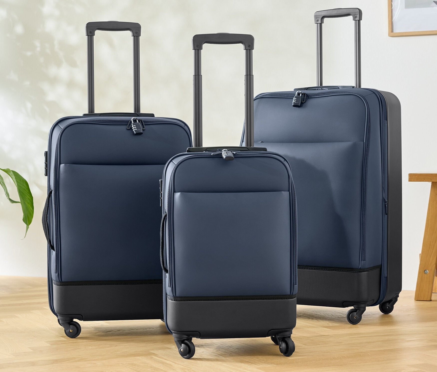 Három hibrid bőrönd (kicsi, közepes és nagy) áll a fapadlón.